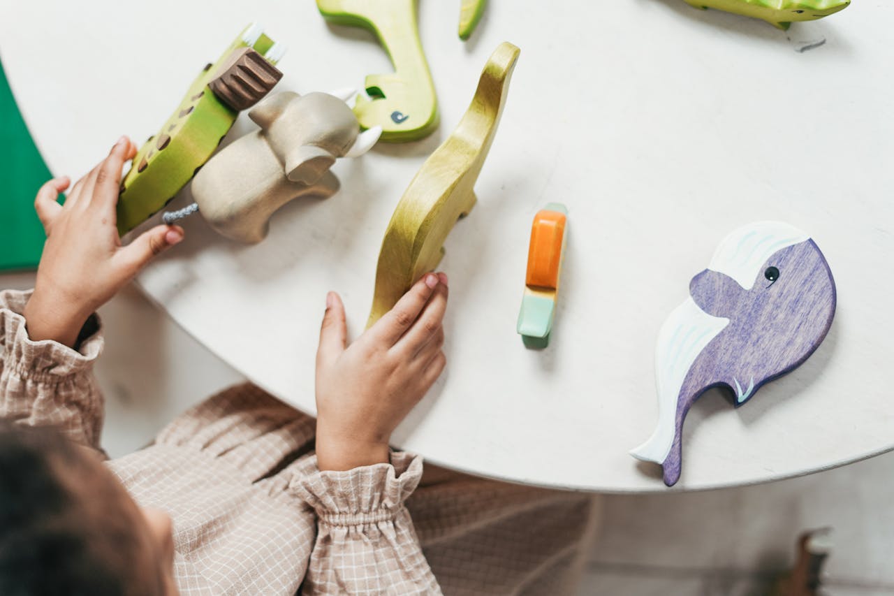 A young child is engaged in play with colorful wooden toys on a white table.