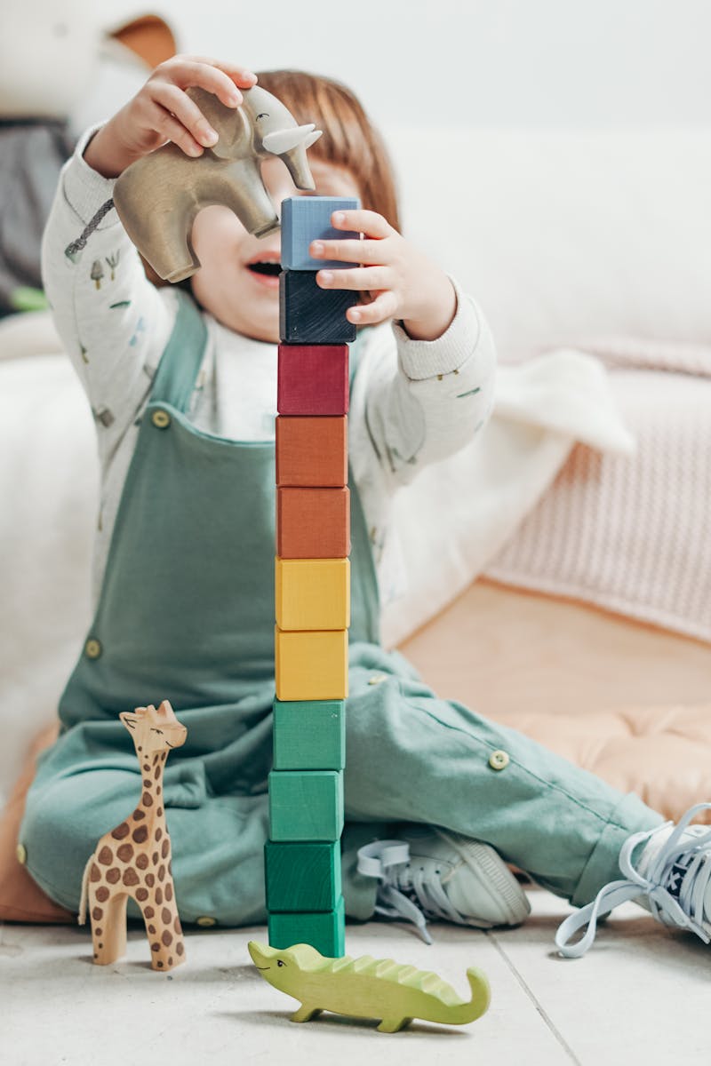 A young child engaged in creative play with colorful wooden blocks indoors.